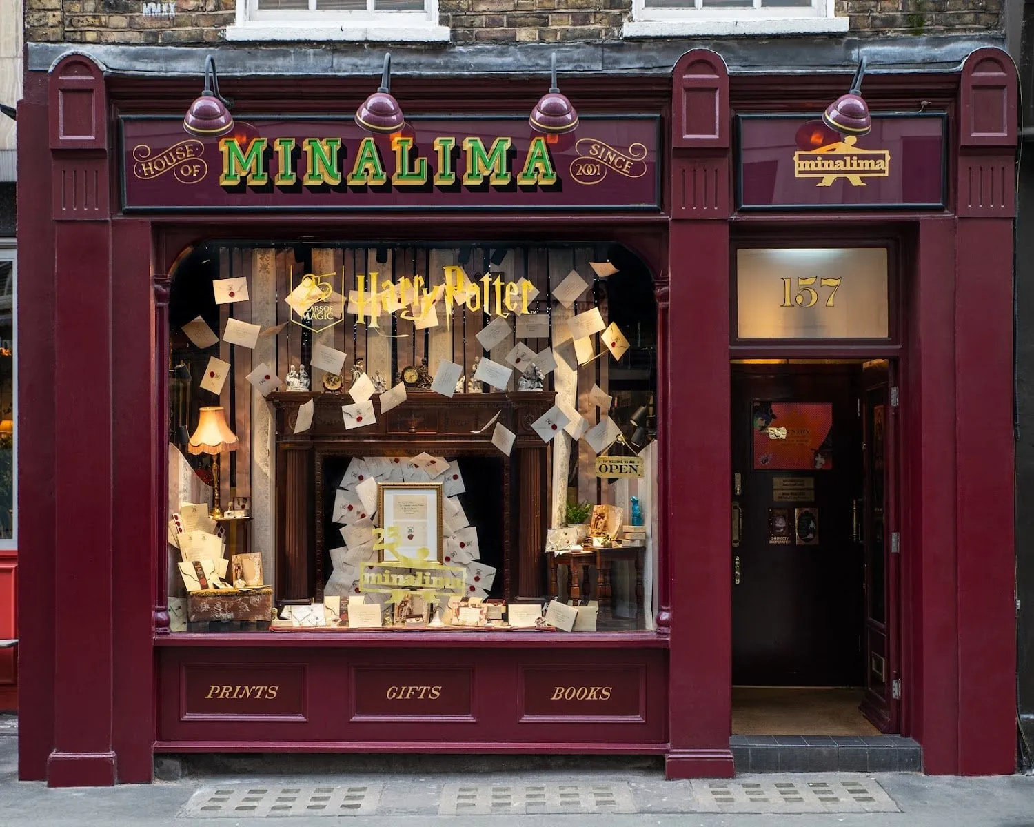 The maroon shopfront of House of MinaLima at 157 Wardour Street, its window full of Hogwarts letters flying out of a fireplace, with Prints, Gifts and Books painted beneath