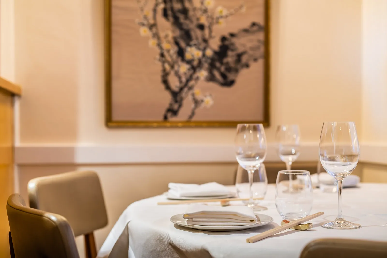 A table laid with glasses and chopsticks beside a framed painting