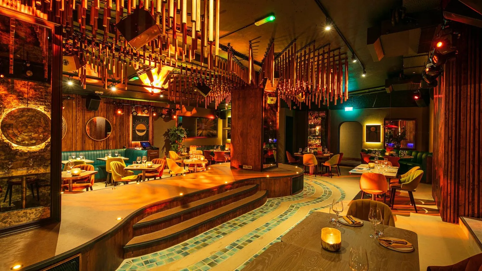 INCA's dining room, with tables round a central stage under a canopy of hanging copper tubes