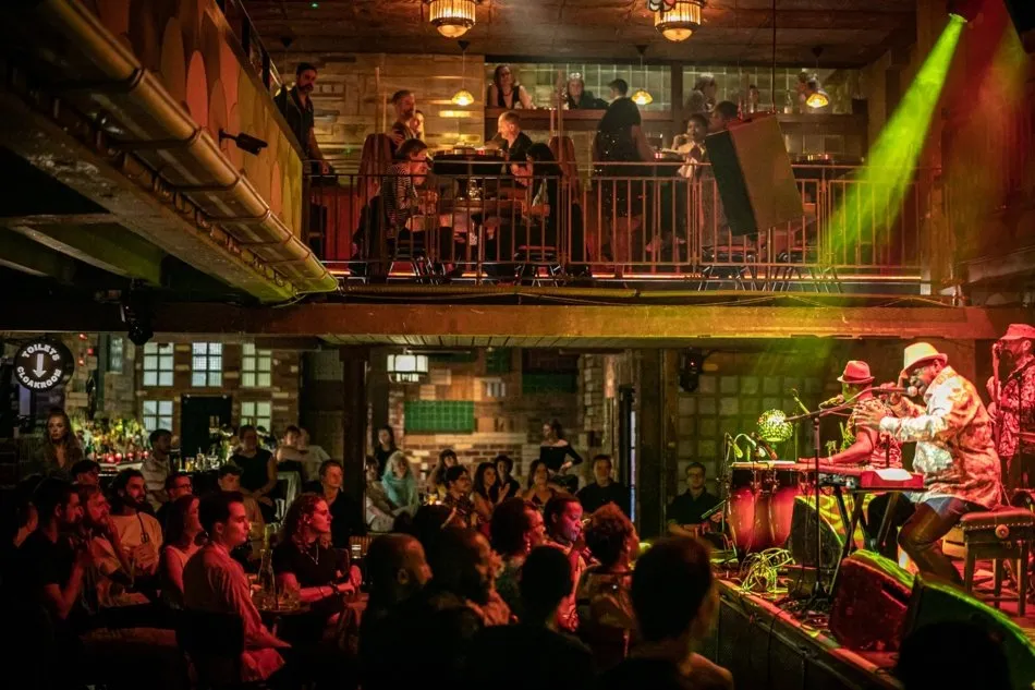 Diners eat on the first-floor mezzanine at the Jazz Cafe, looking down on a band playing on the stage below