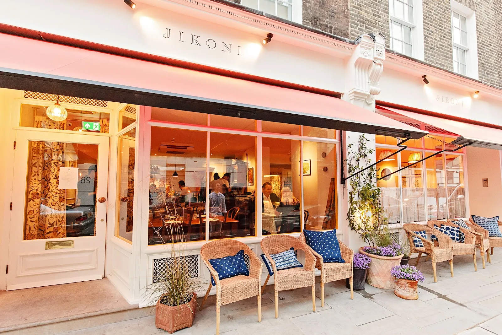 The pastel peach exterior of Jikoni on Blandford Street in Marylebone with outdoor cane chairs and planters