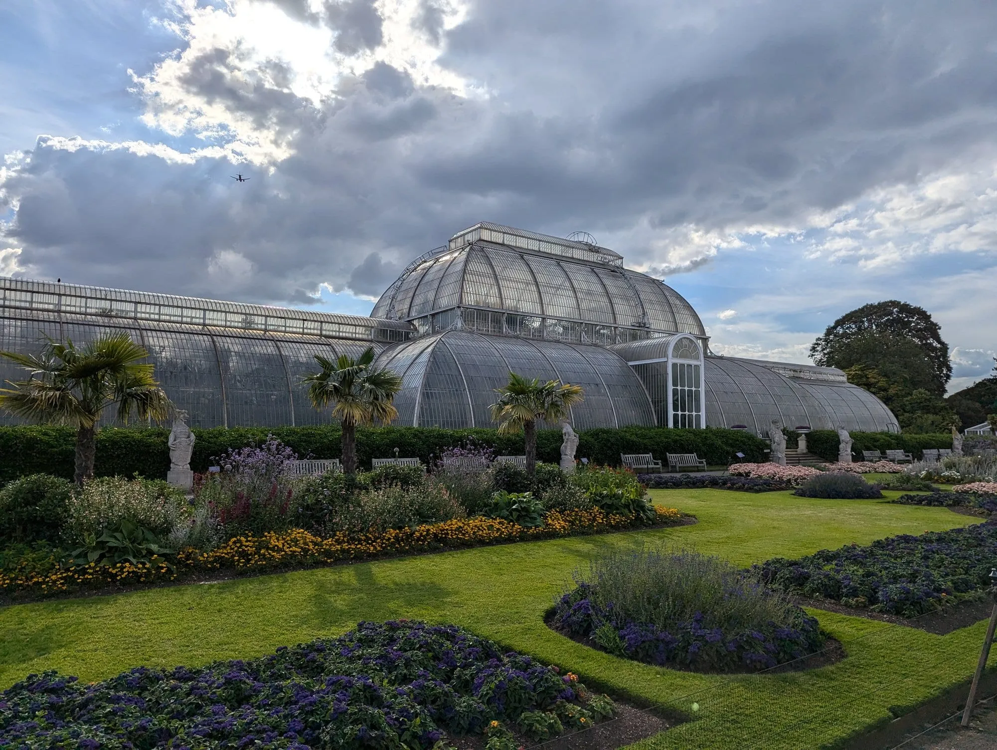 The curved glass and iron Palm House at Kew Gardens, framed by lawns and formal flowerbeds