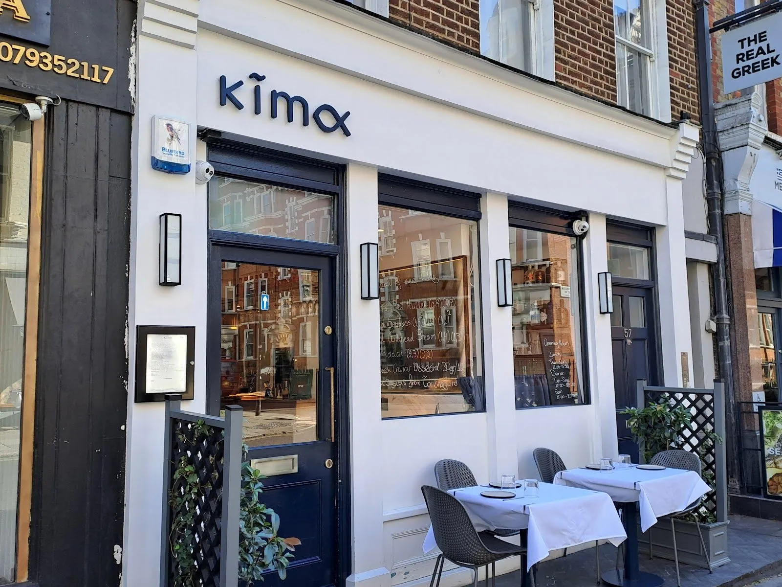 Kima's white shopfront on Paddington Street, with its name in navy lettering, tall windows and two pavement tables laid with white cloths