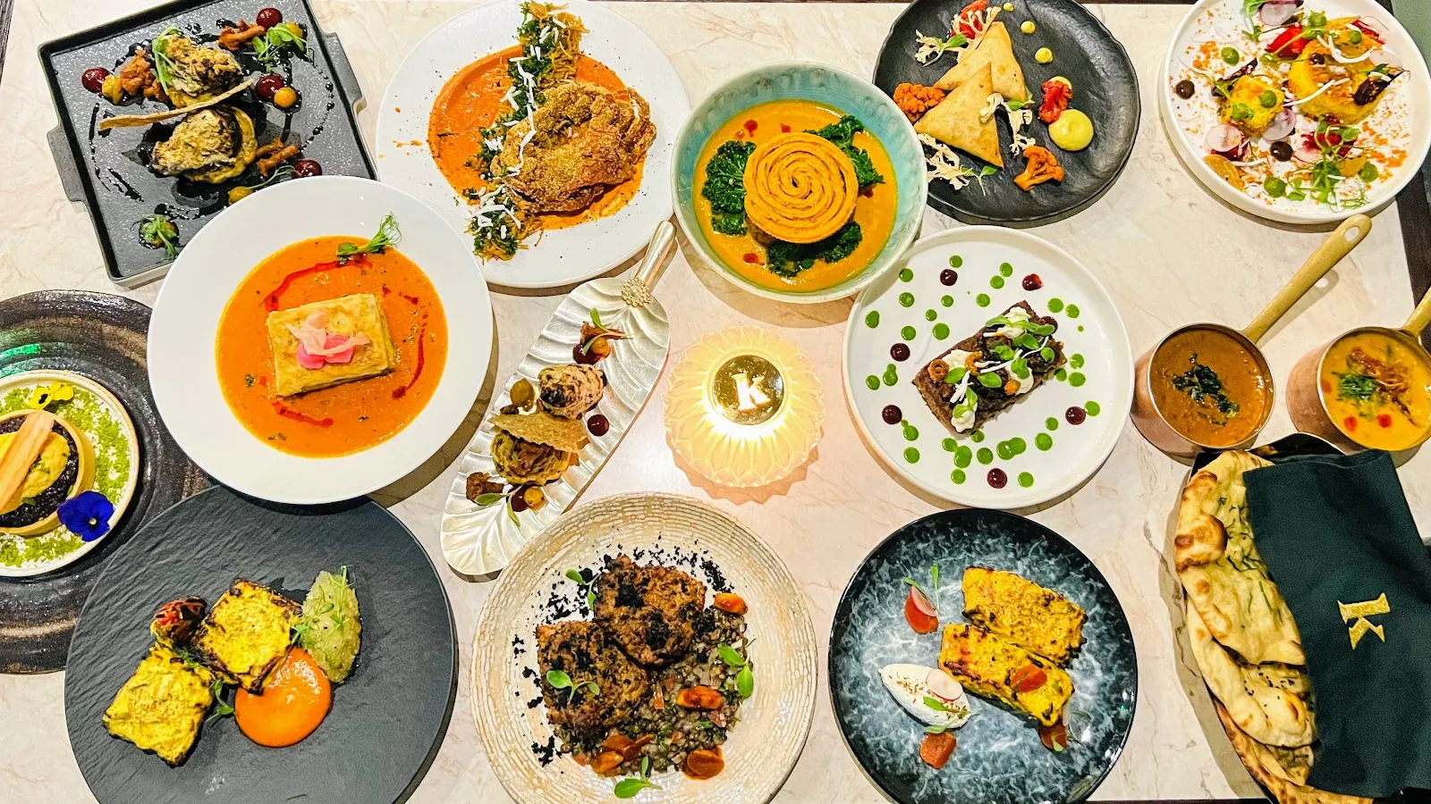 A table spread of small dishes, samosas and copper pots of dal at Kutir