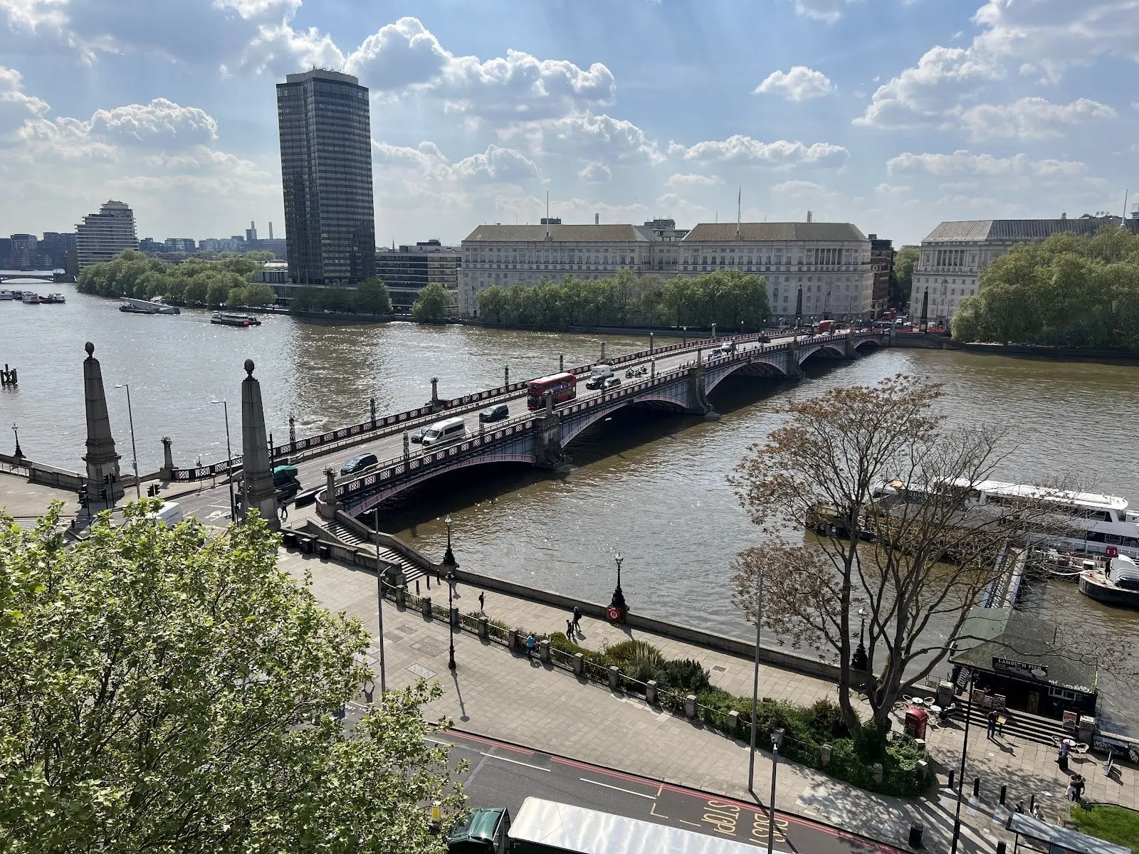 Lambeth Bridge from above on the Lambeth side, a red double-decker crossing among cars, with Millbank Tower and the stone offices along Millbank across the river