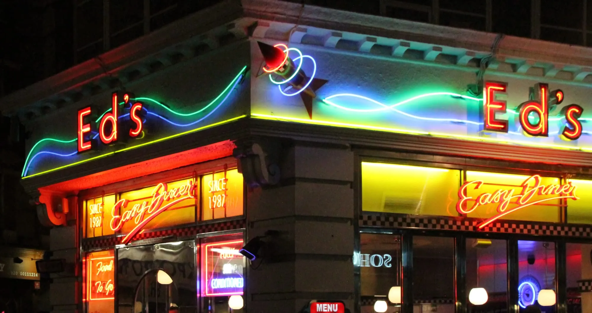 A neon diner sign glowing on a London street at night