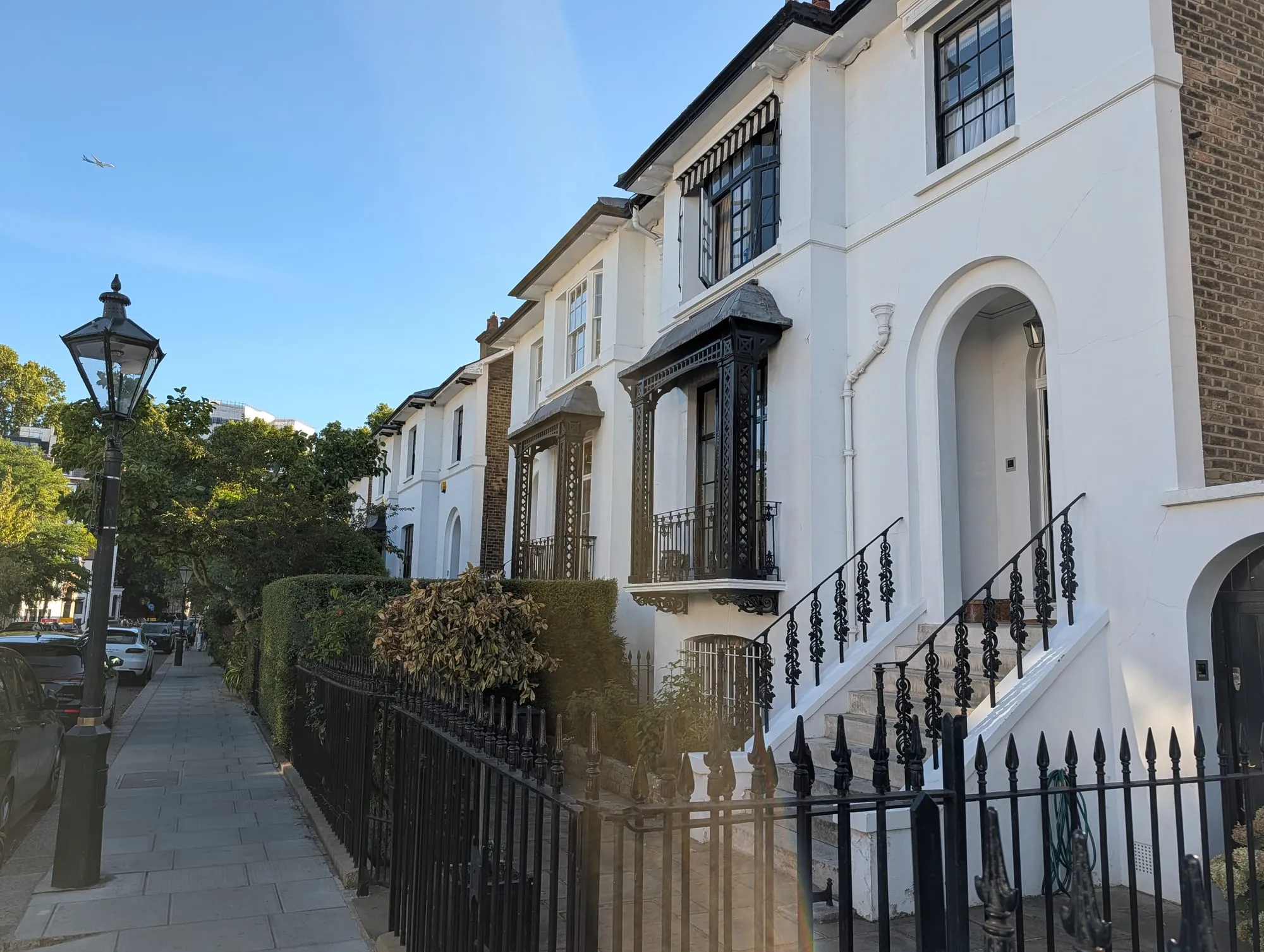 White stucco houses with porticos and iron railings along Launceston Place at dusk