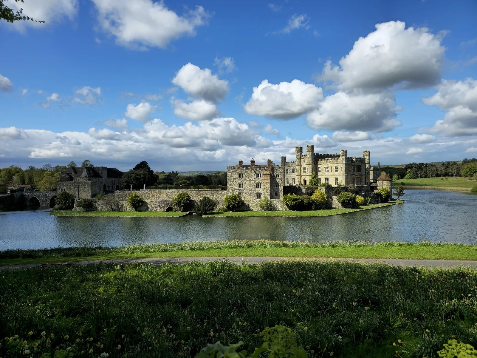 Leeds Castle across its moat, under a blue sky of white cloud