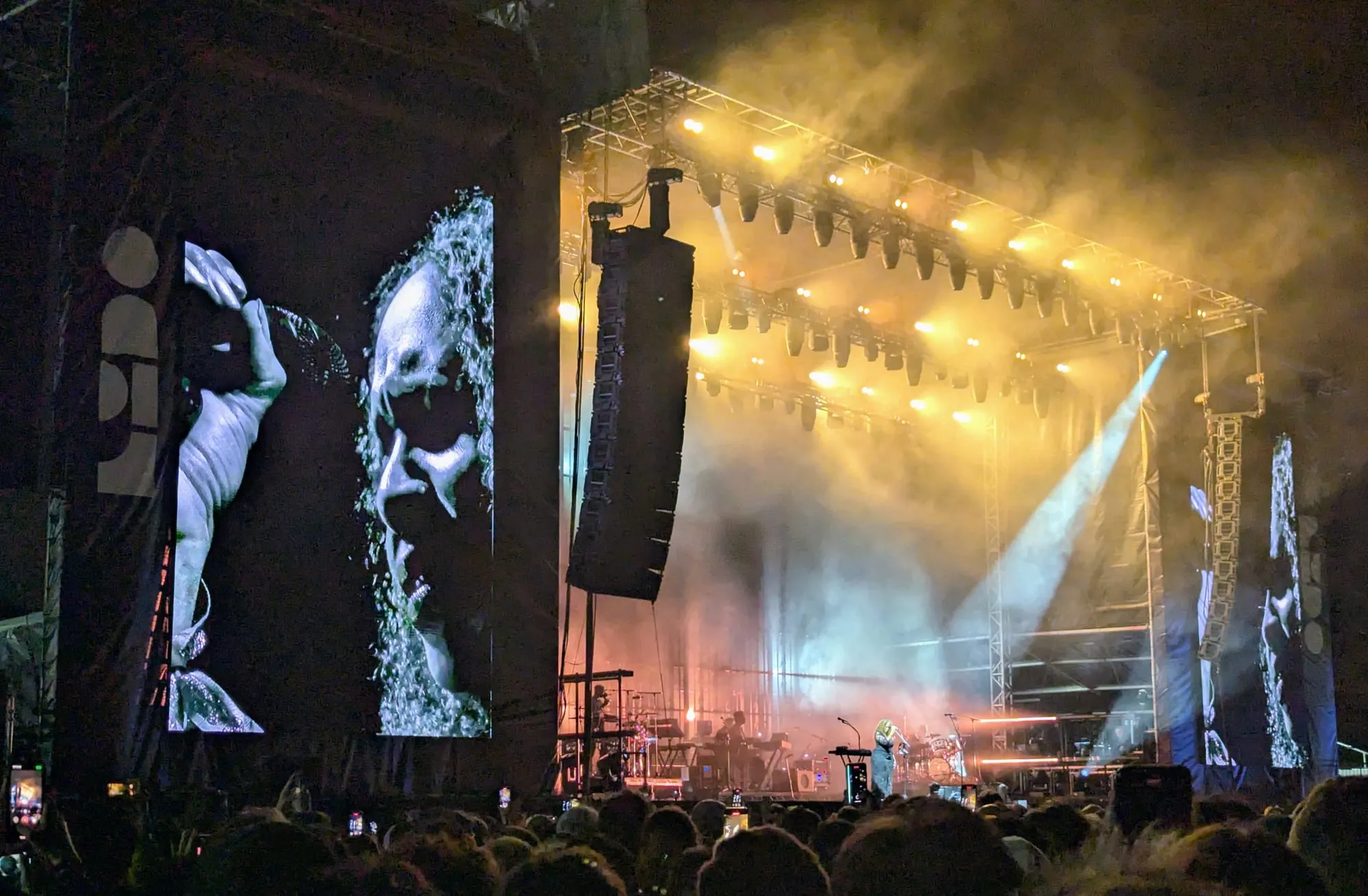 LIDO's main stage at night, lit gold through haze, with the LIDO name running down the big screen on the left and the crowd in silhouette