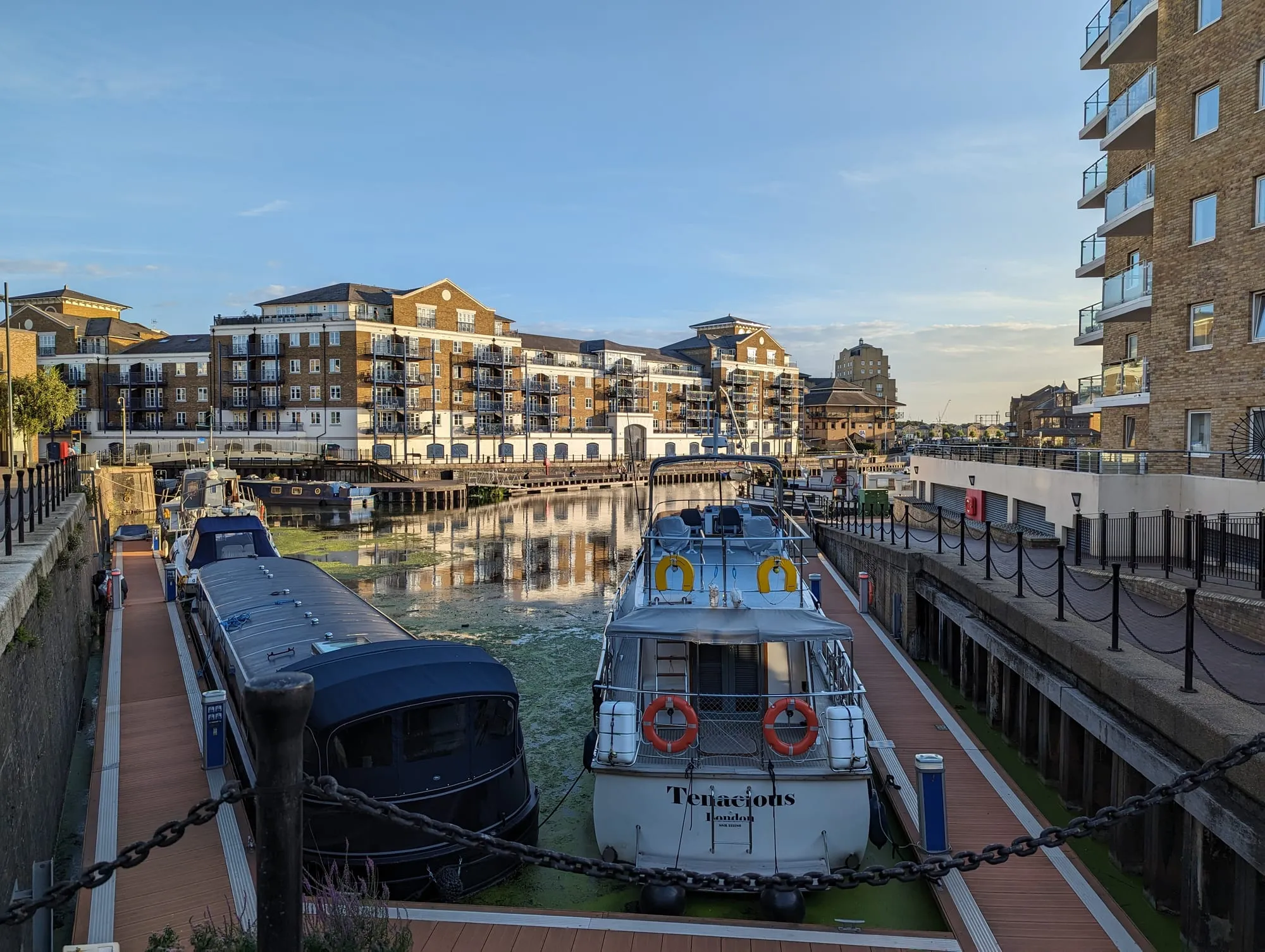 Narrowboats and cruisers moored in Limehouse Basin, surrounded by brick apartment buildings