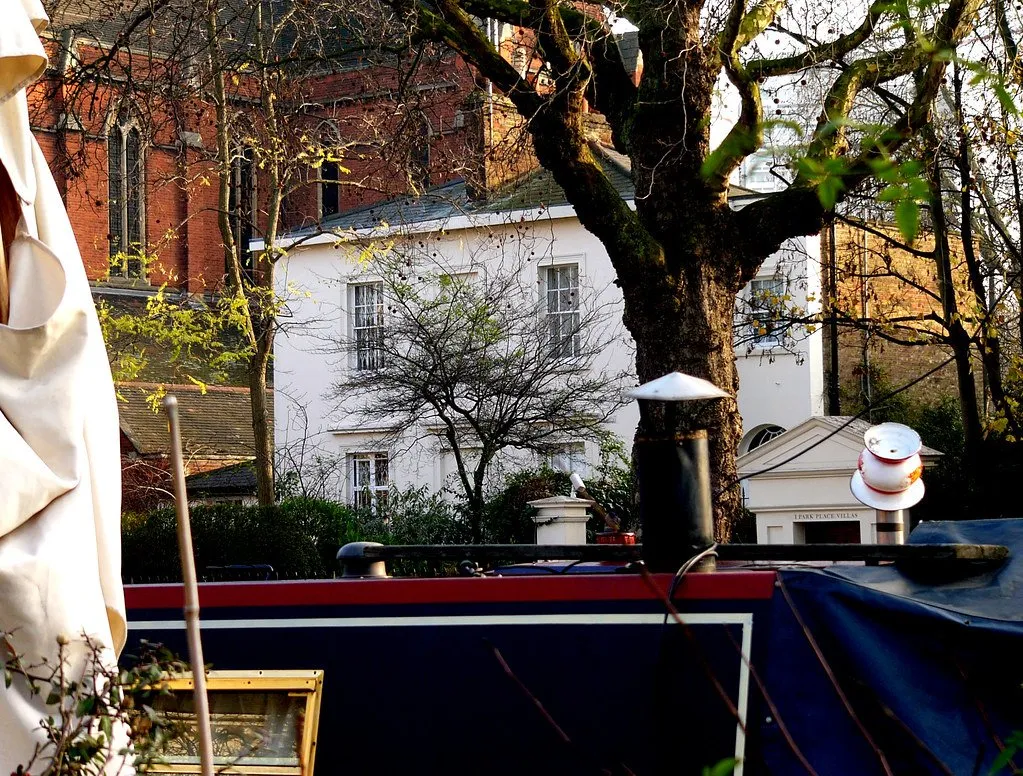 A narrowboat moored at Little Venice, with white stucco villas and a church behind