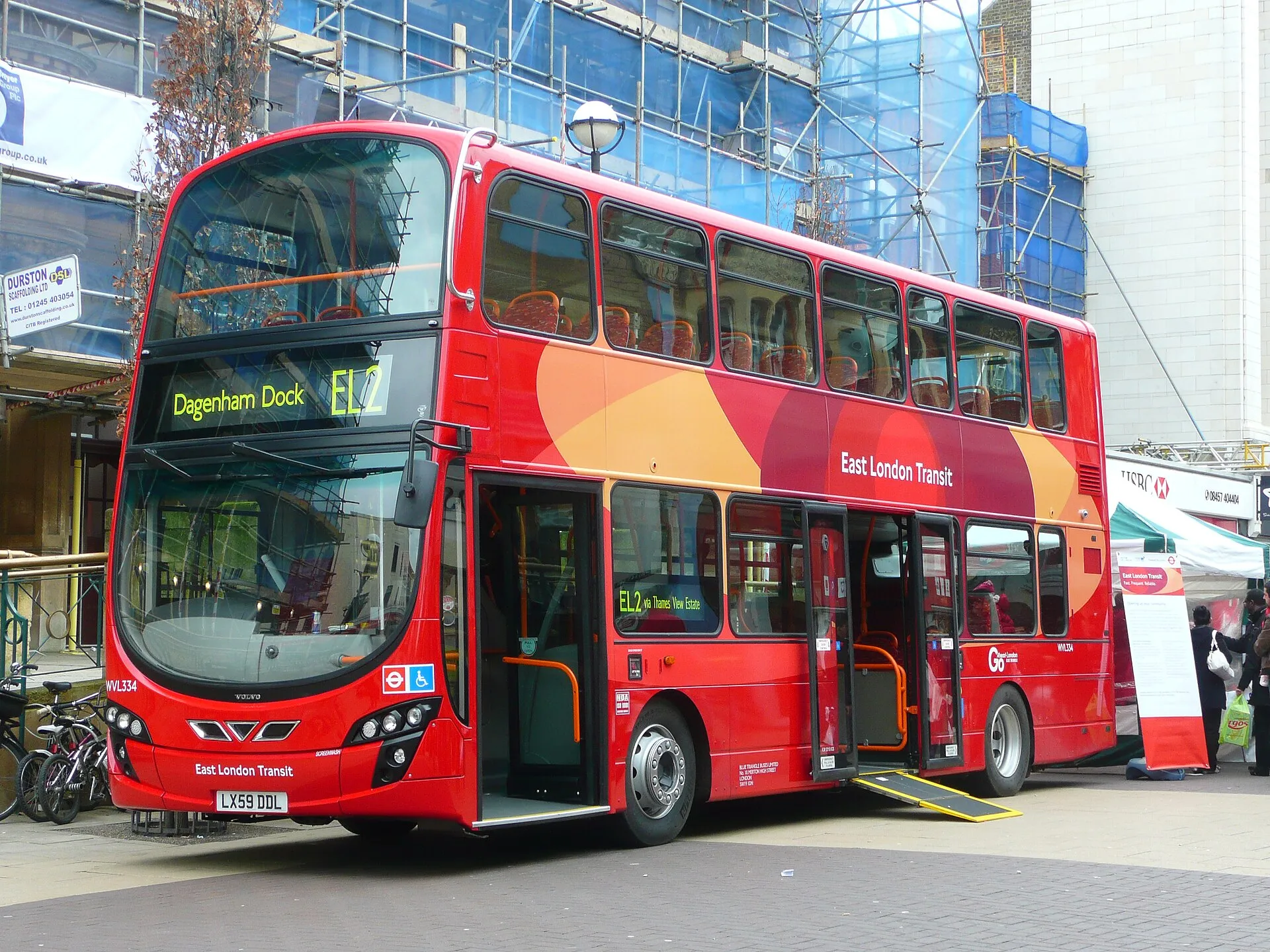 A red London double-decker with its centre-door ramp lowered to the pavement, the wheelchair symbol on the front beside the roundel