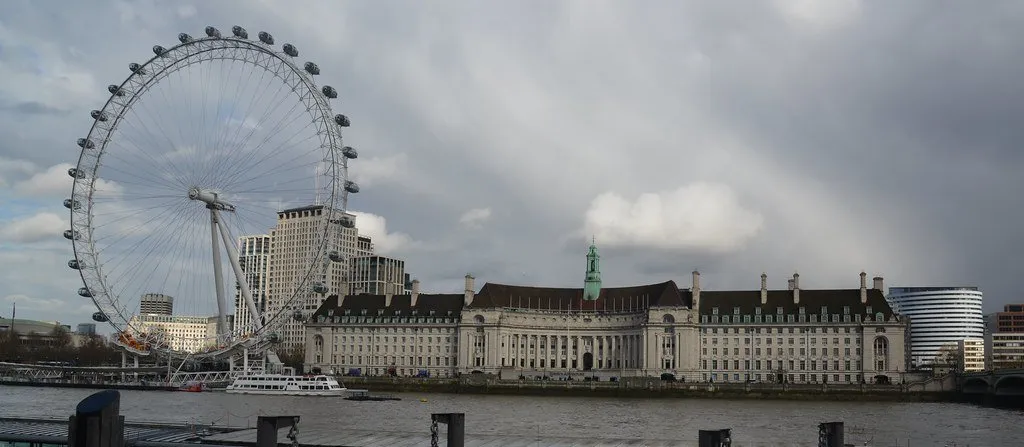 The London Eye turning behind the curved stone frontage of County Hall on the South Bank