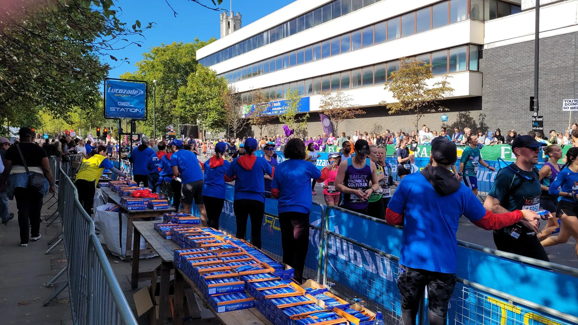 Volunteers behind trestle tables of energy gels at a Lucozade Sport gel station on the London Marathon course