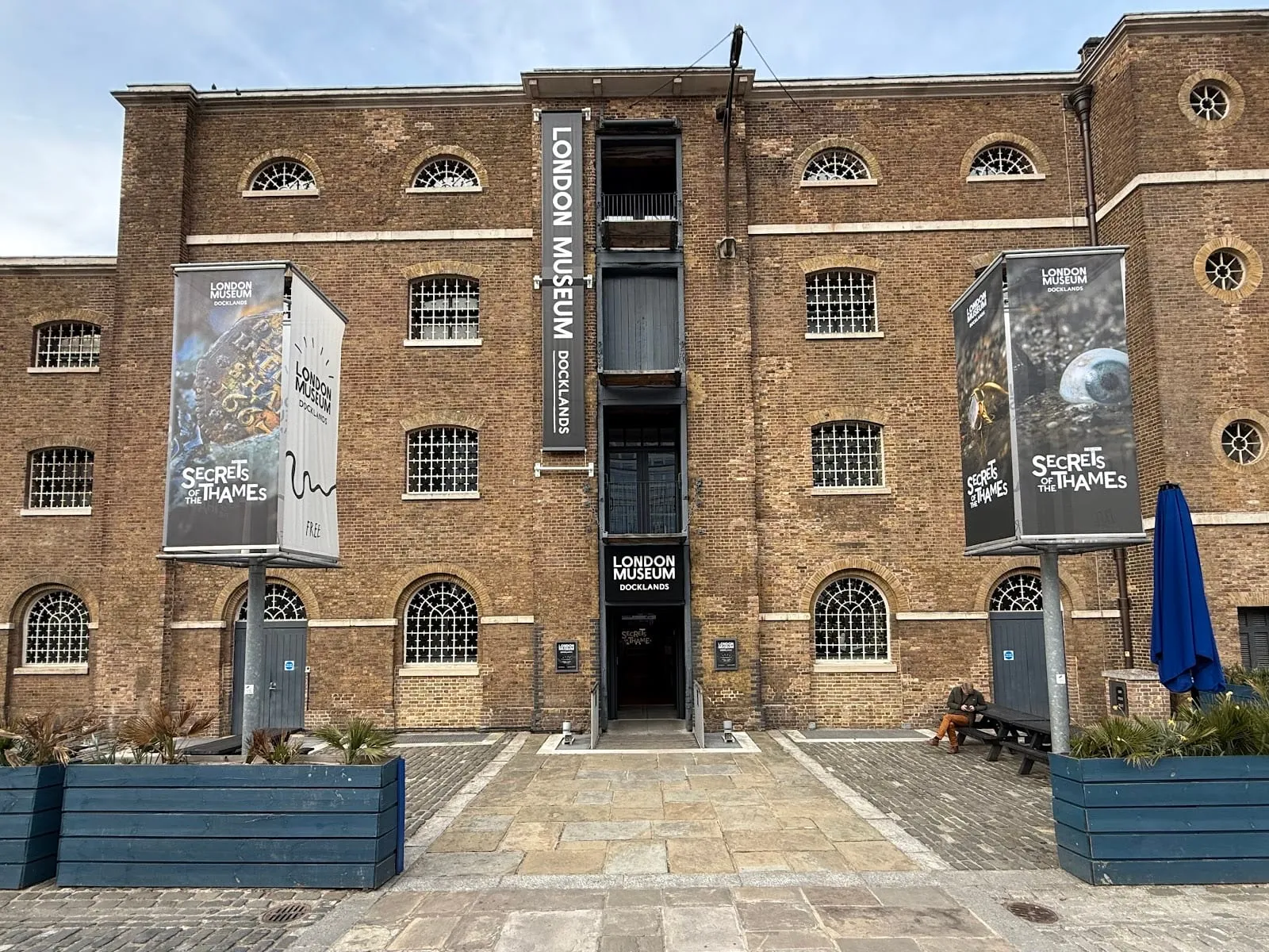The brick facade of the Georgian warehouse housing London Museum Docklands, with banners for the Secrets of the Thames exhibition