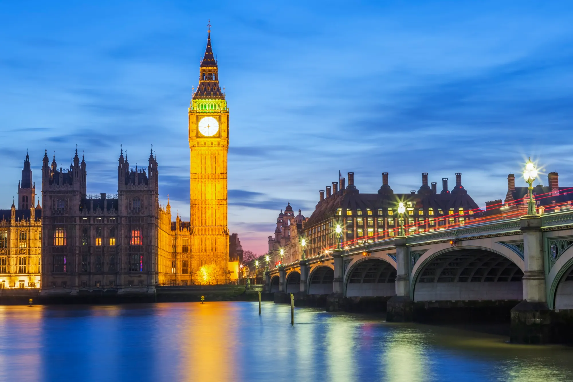 Elizabeth Tower and Westminster Bridge illuminated beside the Thames at blue hour