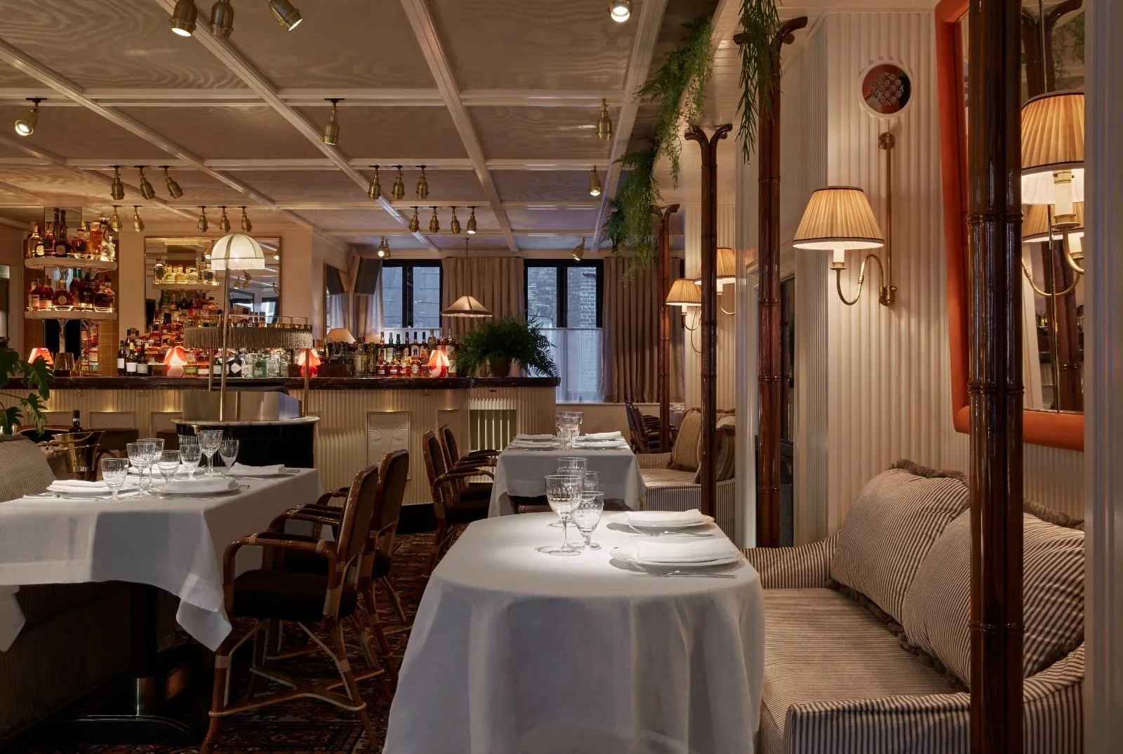 Louie's dining room, with linen-covered tables, bamboo-style pillars and striped banquettes in front of the bar