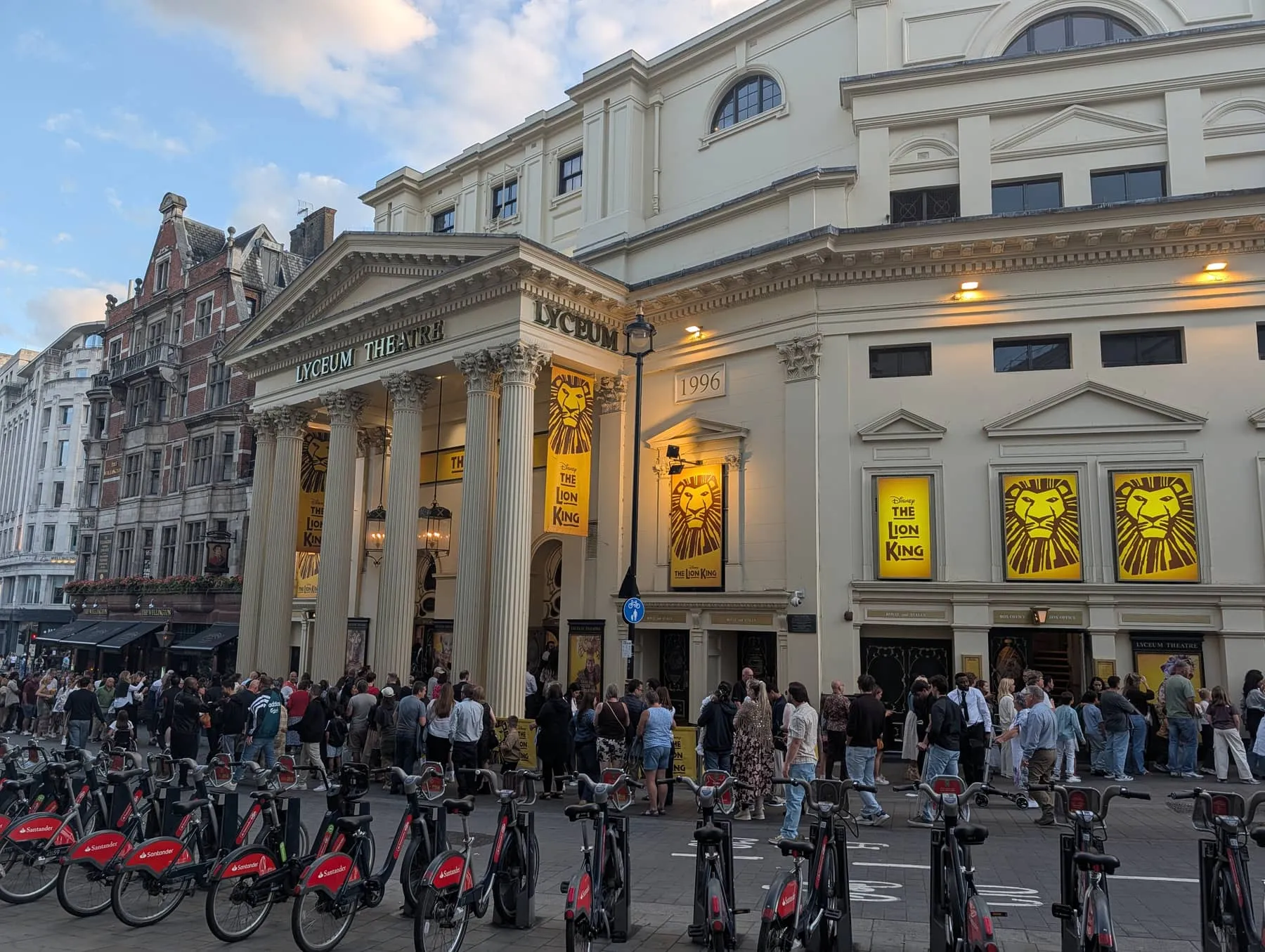 The colonnaded front of the Lyceum Theatre on Wellington Street, with The Lion King billboards and a rank of hire bikes outside