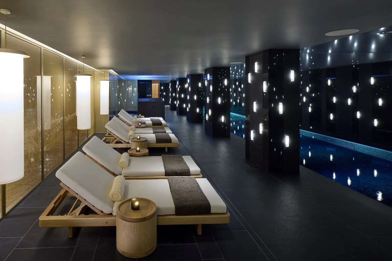 The indoor pool at Mandarin Oriental Mayfair, with a row of loungers and dark walls lit by small lights