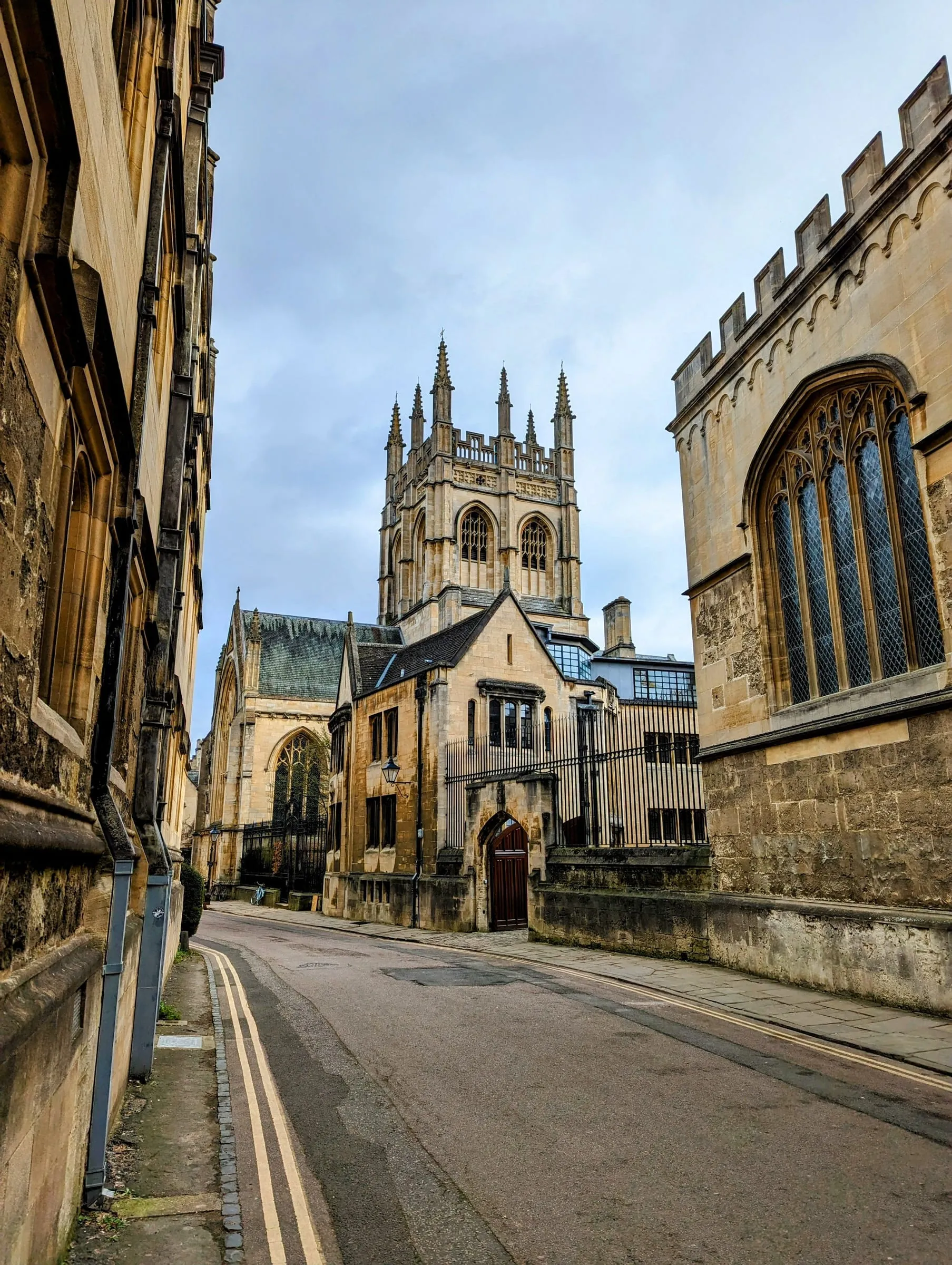 Merton College's tower above Merton Street, with the college's windows and a stone wall running down the empty cobbled lane