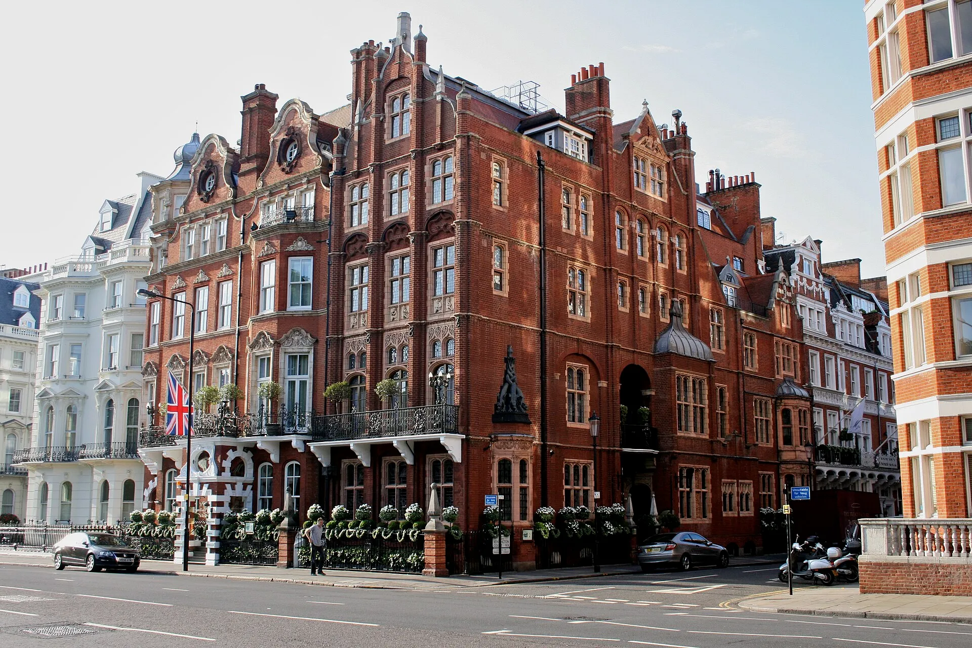 The Milestone Hotel's red-brick Victorian frontage on the corner of Kensington Court, with ornate gables, iron balconies, clipped topiary along the railings and a Union flag over the entrance