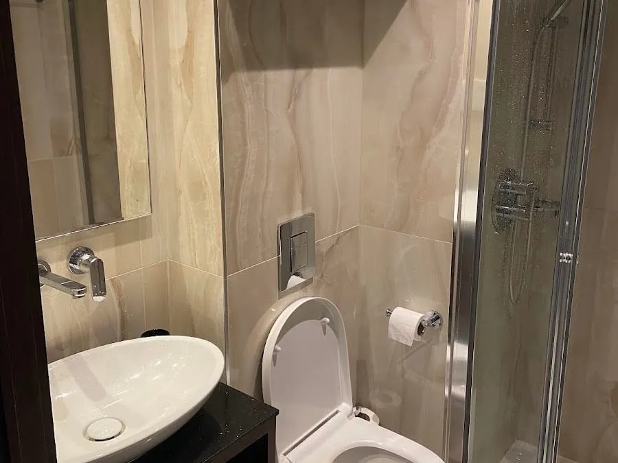 A small bathroom at Montcalm Chilworth Townhouse with onyx-effect tiles, a bowl basin on a black counter and a corner glass shower