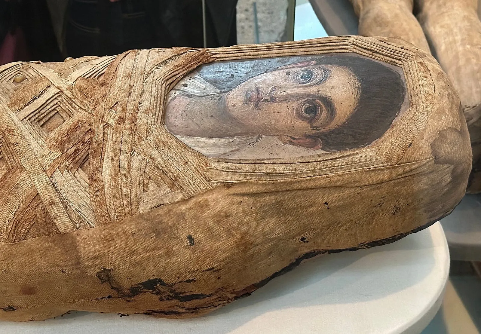 A wrapped mummy with a painted portrait panel of a young face set into the linen bandages