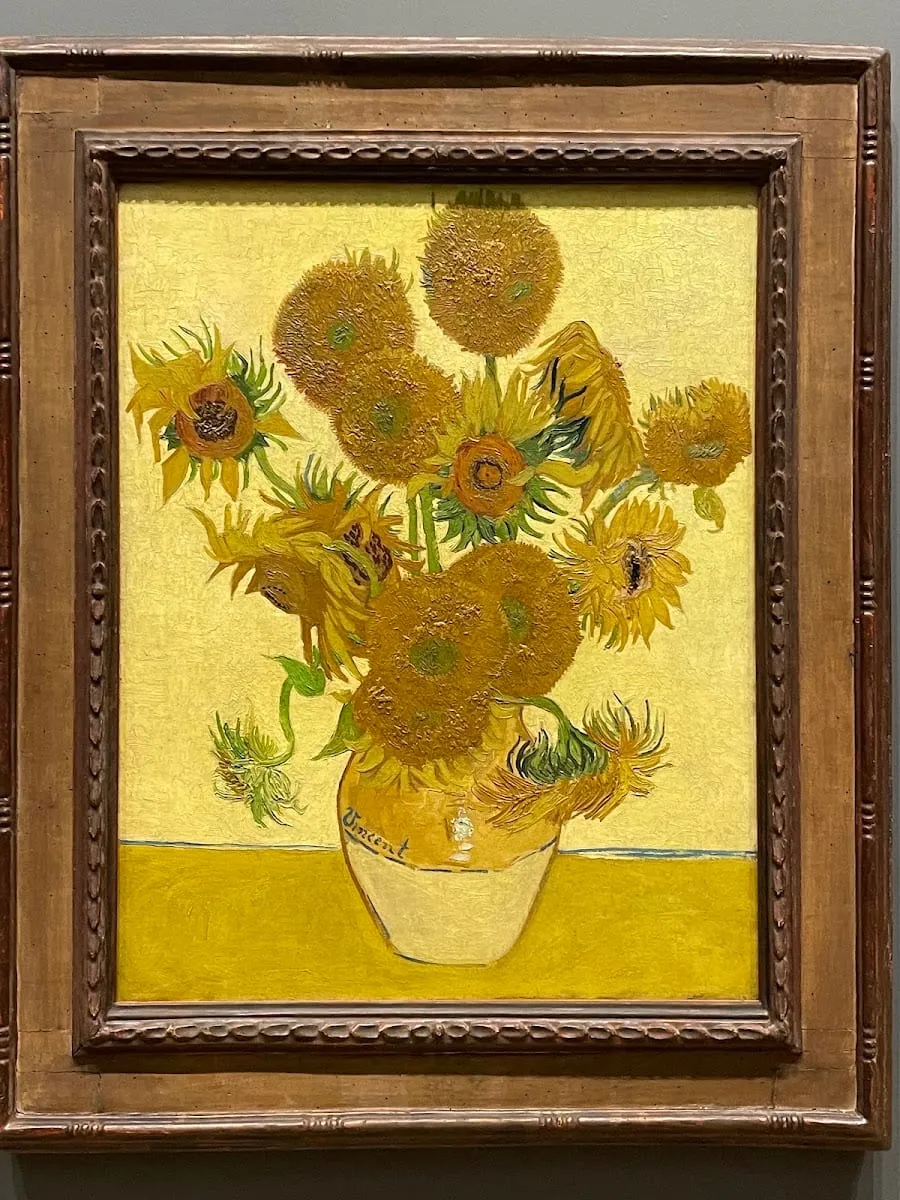Van Gogh's Sunflowers painting in a gilt frame, showing a vase of yellow sunflowers signed 'Vincent'