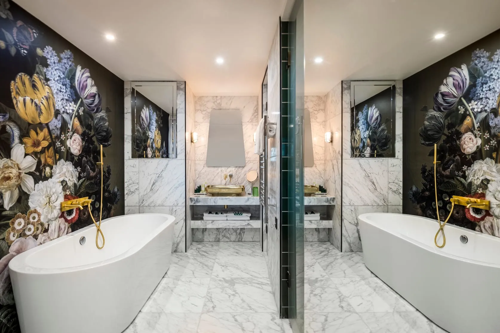 A bathroom at nhow London with dark floral wallpaper, a freestanding tub and gold fixtures