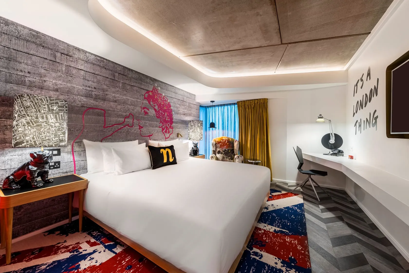 A room at nhow London with a Union Jack rug, a graphic portrait on the headboard wall and "IT'S A LONDON THING" painted on the wall