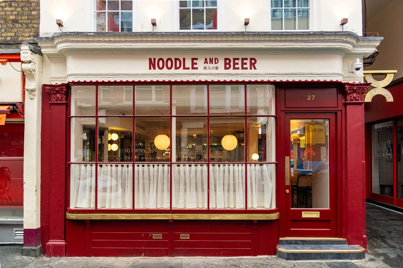 Noodle and Beer's red shopfront at 27 Wardour Street, with round paper lanterns visible through the window