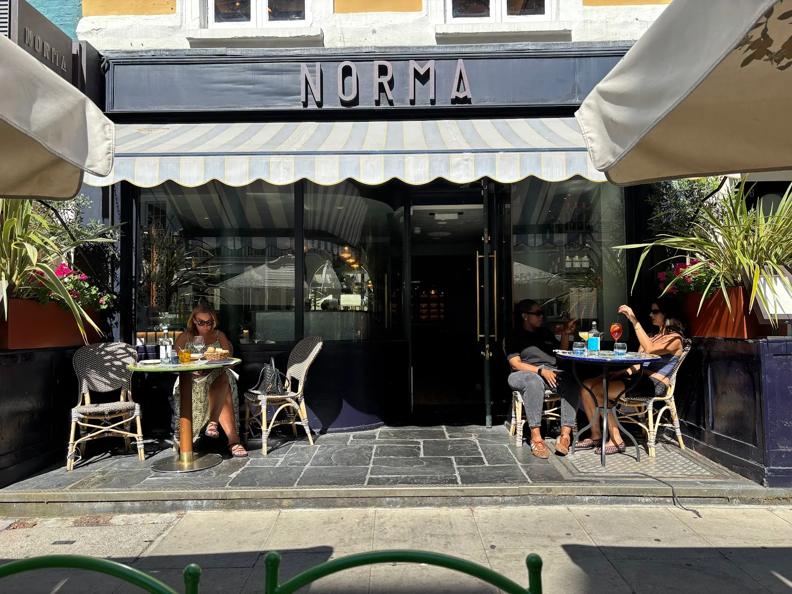 The Norma frontage on a sunny day, with diners at outdoor tables under a striped awning