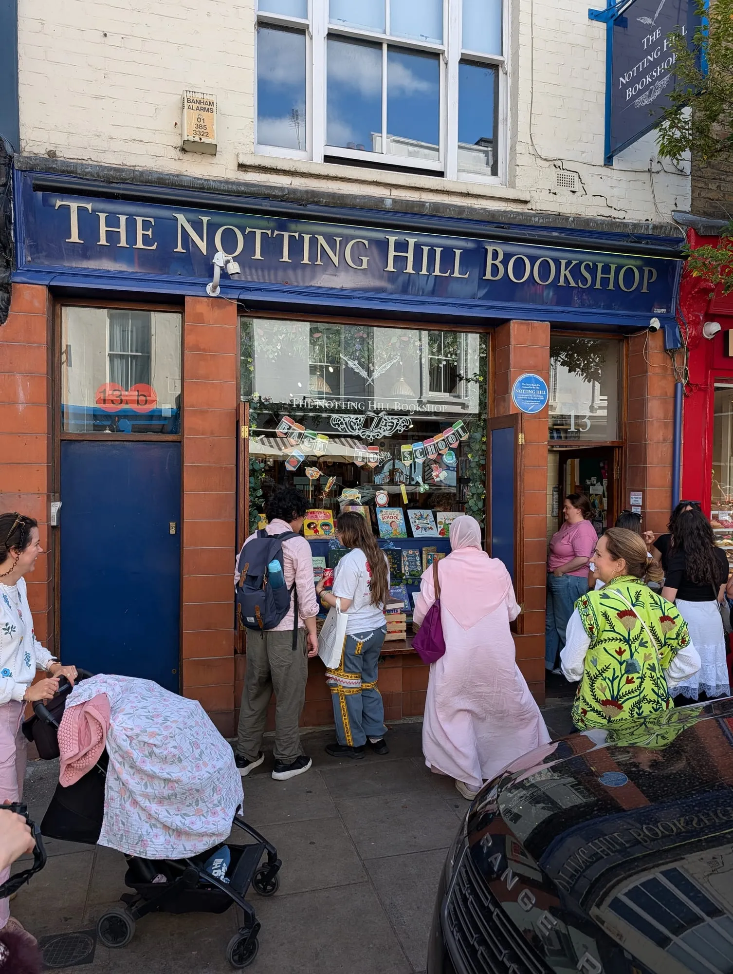 The Notting Hill Bookshop on Blenheim Crescent, a navy and red shopfront with visitors gathered outside