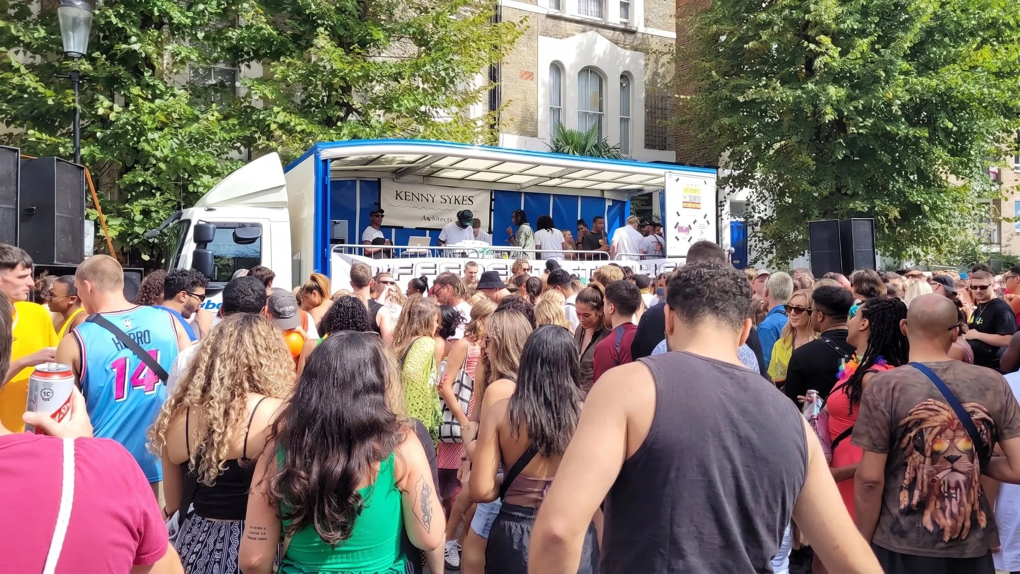 A dense crowd dancing in front of a sound system truck at Notting Hill Carnival
