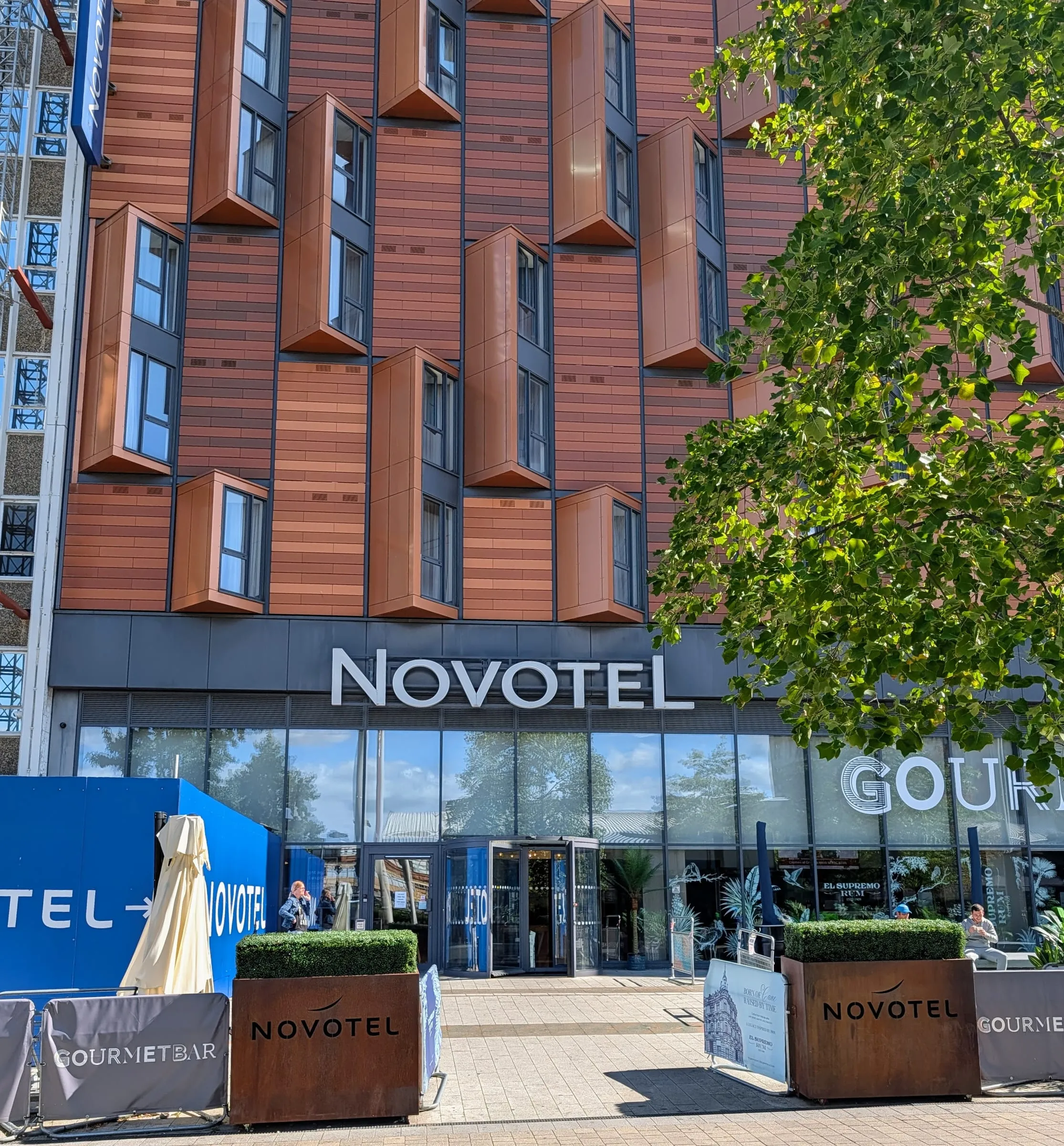 The front of Novotel London Wembley: copper-coloured panels and angled windows above a glass ground floor, the NOVOTEL sign over the entrance