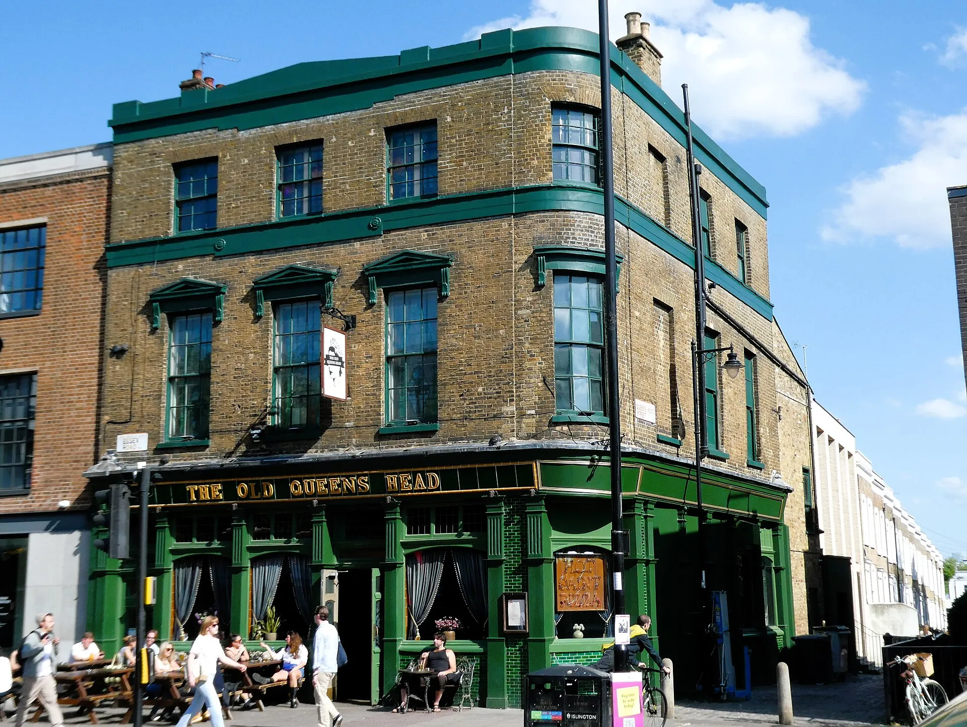 The Old Queen's Head on Essex Road, a three-storey corner pub with a green tiled ground floor and drinkers at tables outside