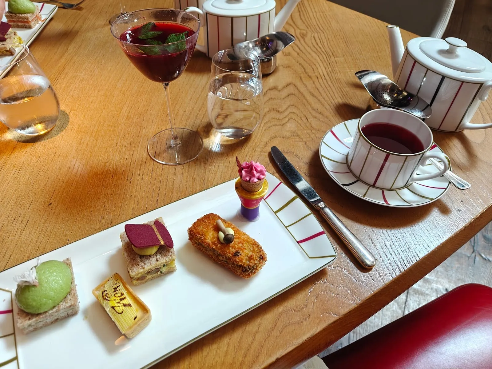 Charlie and the Chocolate Factory afternoon tea at One Aldwych, with themed pastries, a chocolate Wonka tart, mini ice cream cone, cocktail, and striped teapot