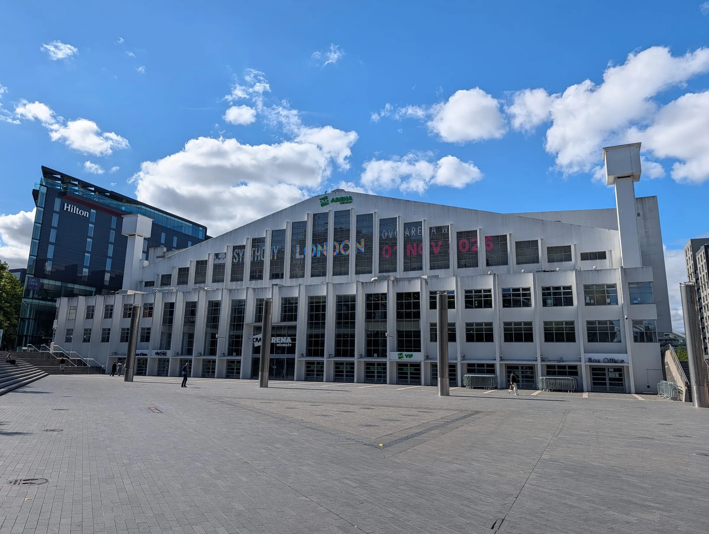 OVO Arena Wembley's white facade across an empty Arena Square, with the Hilton to the left