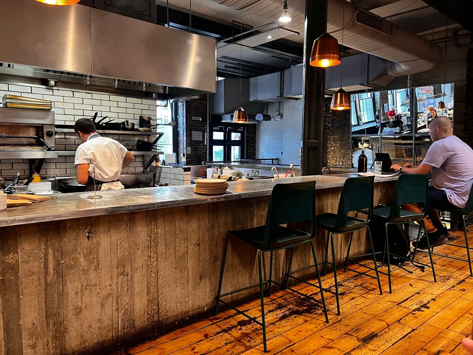 The open kitchen at Ozone Coffee Roasters, with a chef working at the pass and a customer seated at the counter