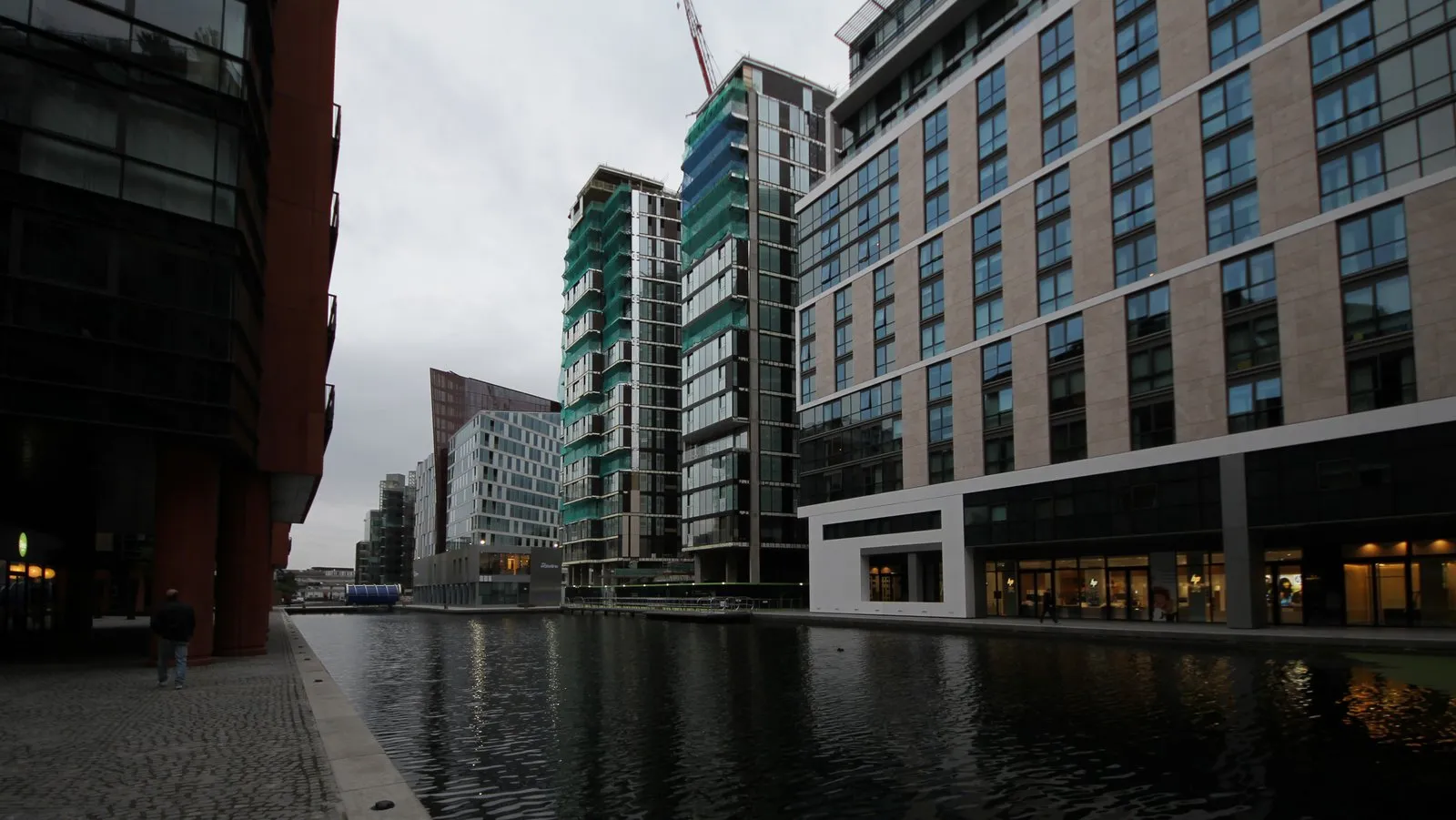 The still water of Paddington Basin lined with modern glass office buildings