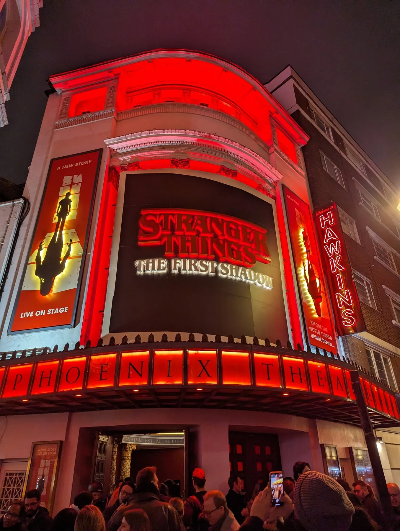 The lit red frontage of the Phoenix Theatre at night, with the audience leaving through the doors after a performance