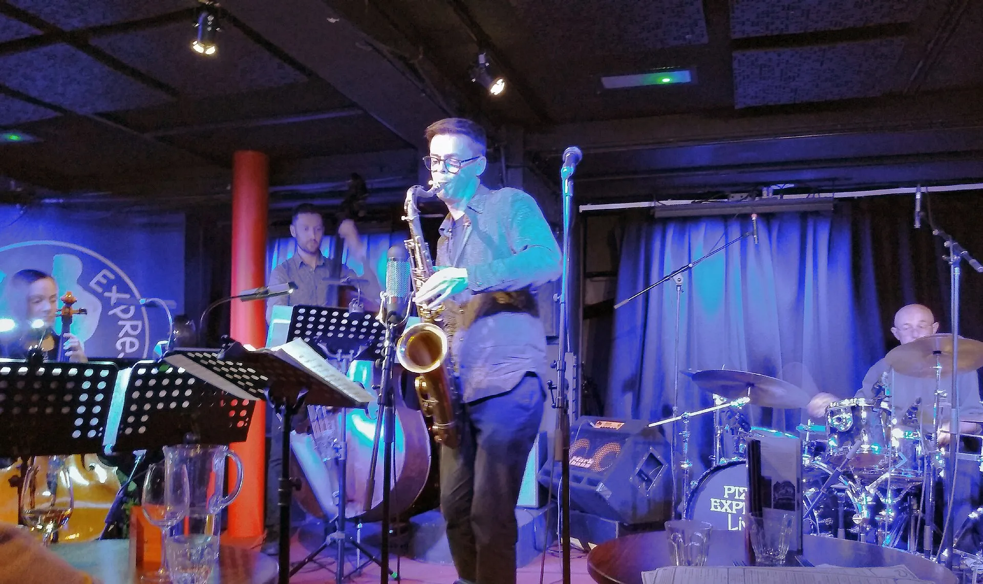A quartet performing on the small stage of the PizzaExpress Jazz Club basement in Soho, the audience seated at tables close to the band
