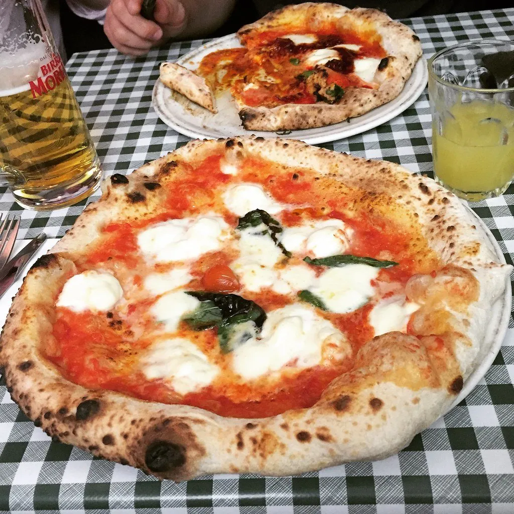 A margherita pizza on a checked tablecloth