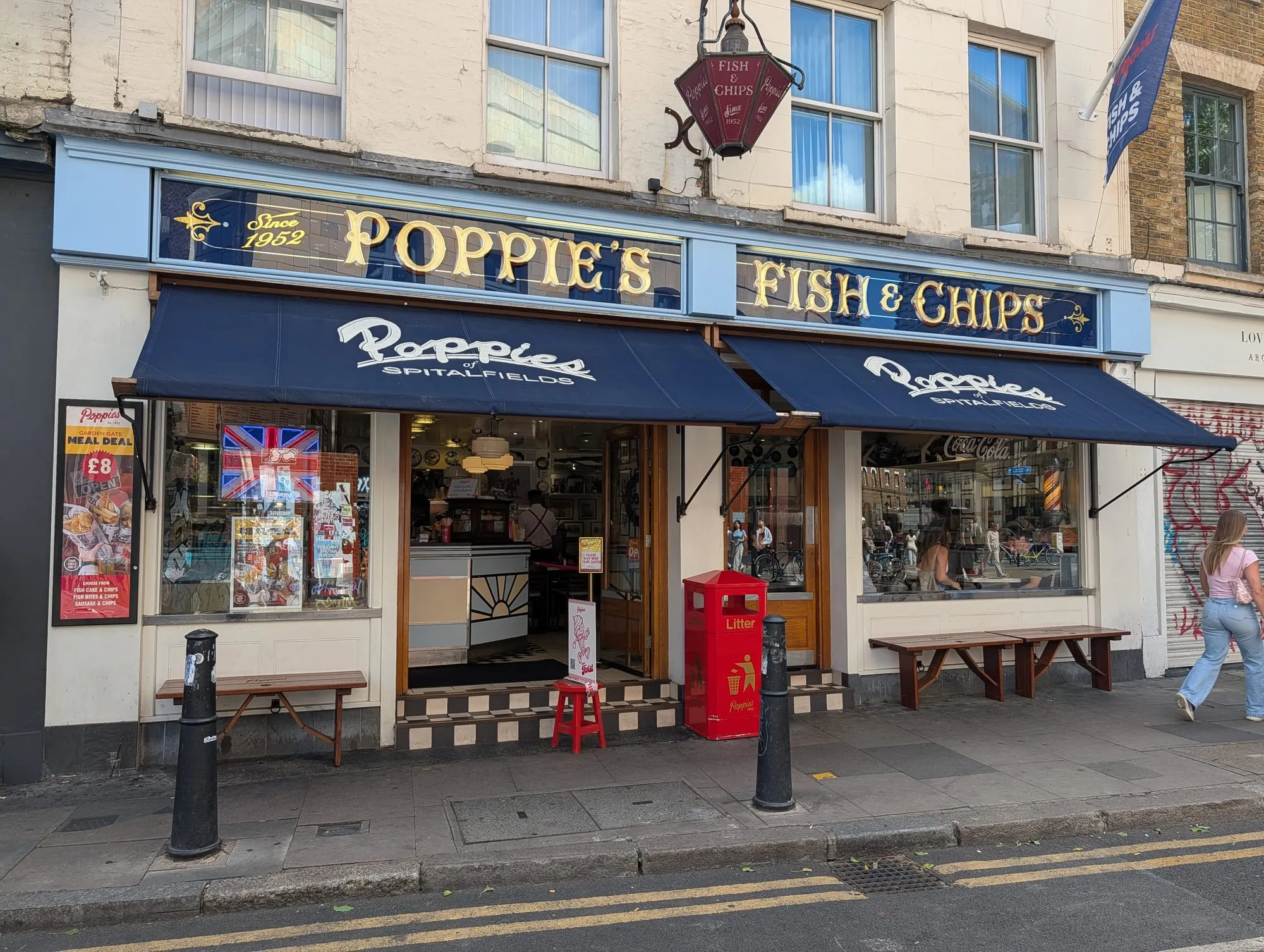 The Poppie's Fish & Chips shopfront in Spitalfields, gold lettering on a blue fascia over a navy awning