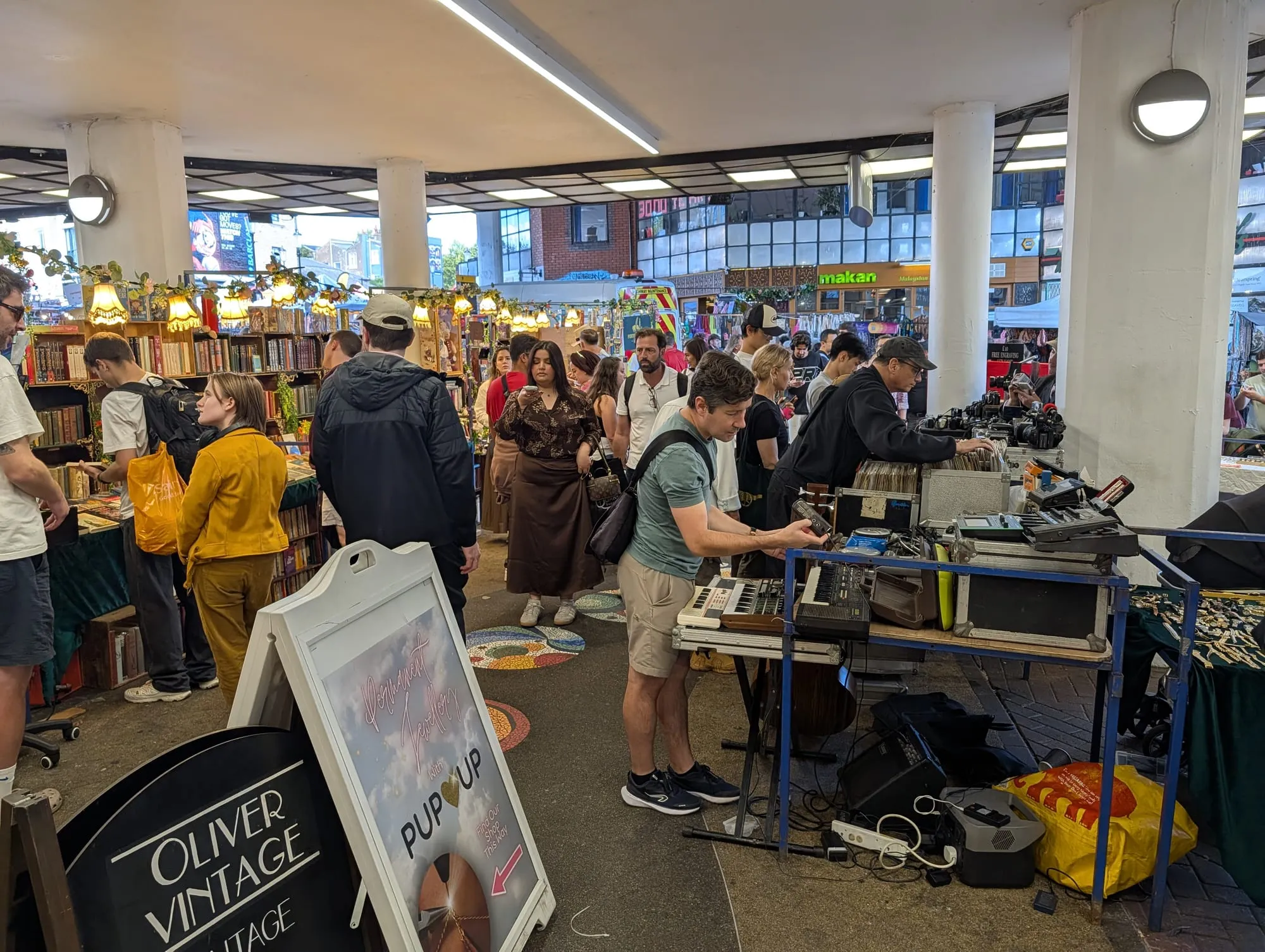 A covered stall of second-hand records and prints under the Westway, with browsers going through the crates