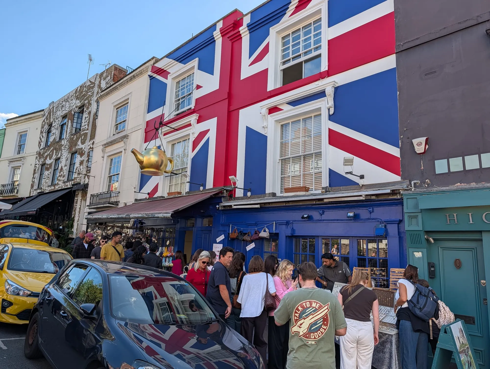 A blue building on Portobello Road with an enormous Union Jack painted across its upper floors, crowds on the pavement below