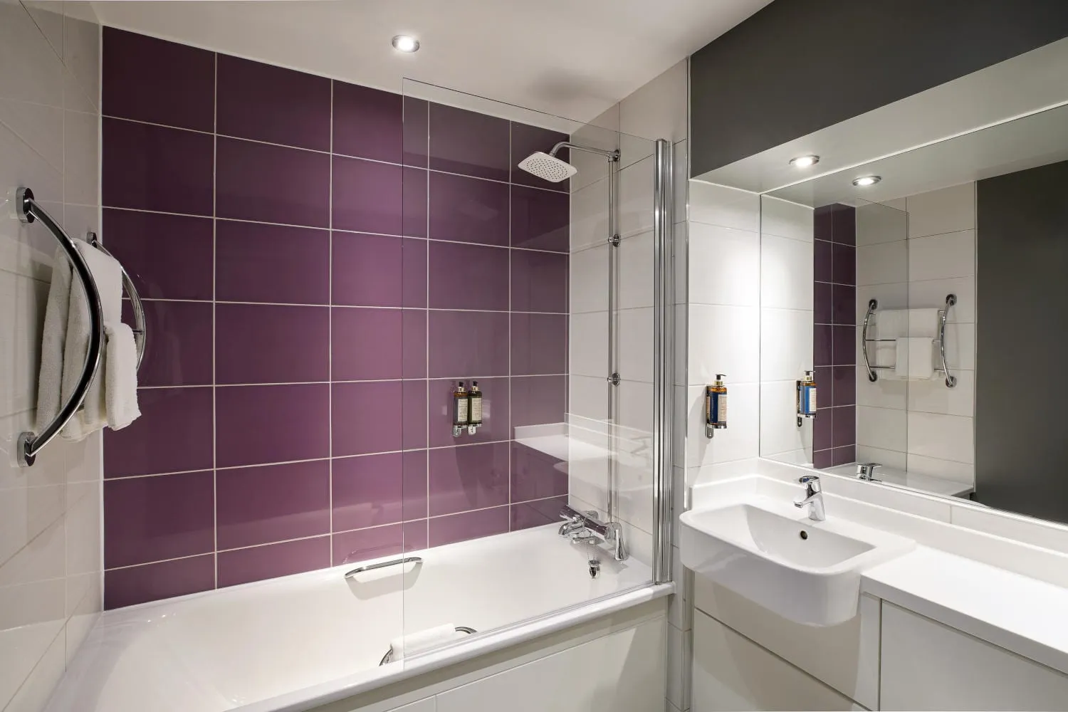 The bathroom at Premier Inn London County Hall, with a purple-tiled bath and shower in the brand's signature accent colour