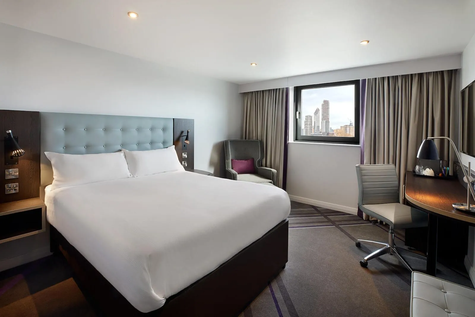 A double room at Premier Inn London Kensington (Earl's Court) with a padded headboard, a desk chair and a window