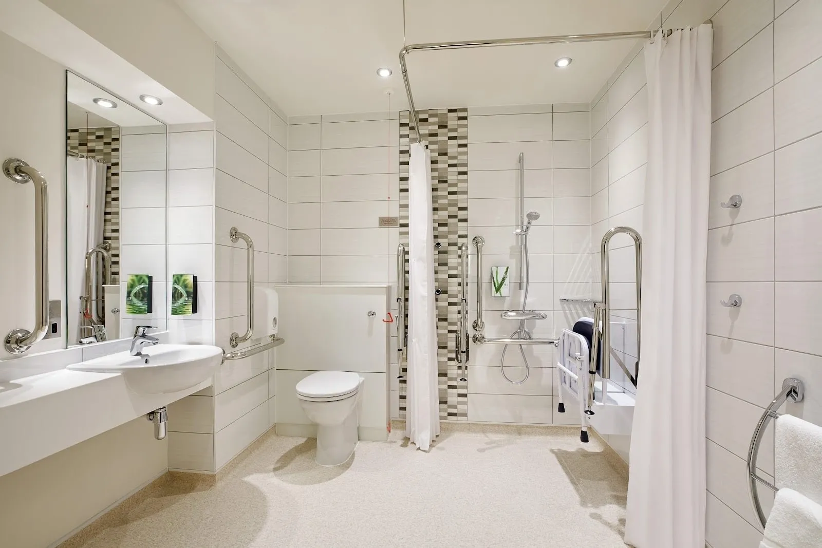 An accessible bathroom at Premier Inn London Woolwich (Royal Arsenal), with grab rails, a fold-down shower seat and a wet-room shower
