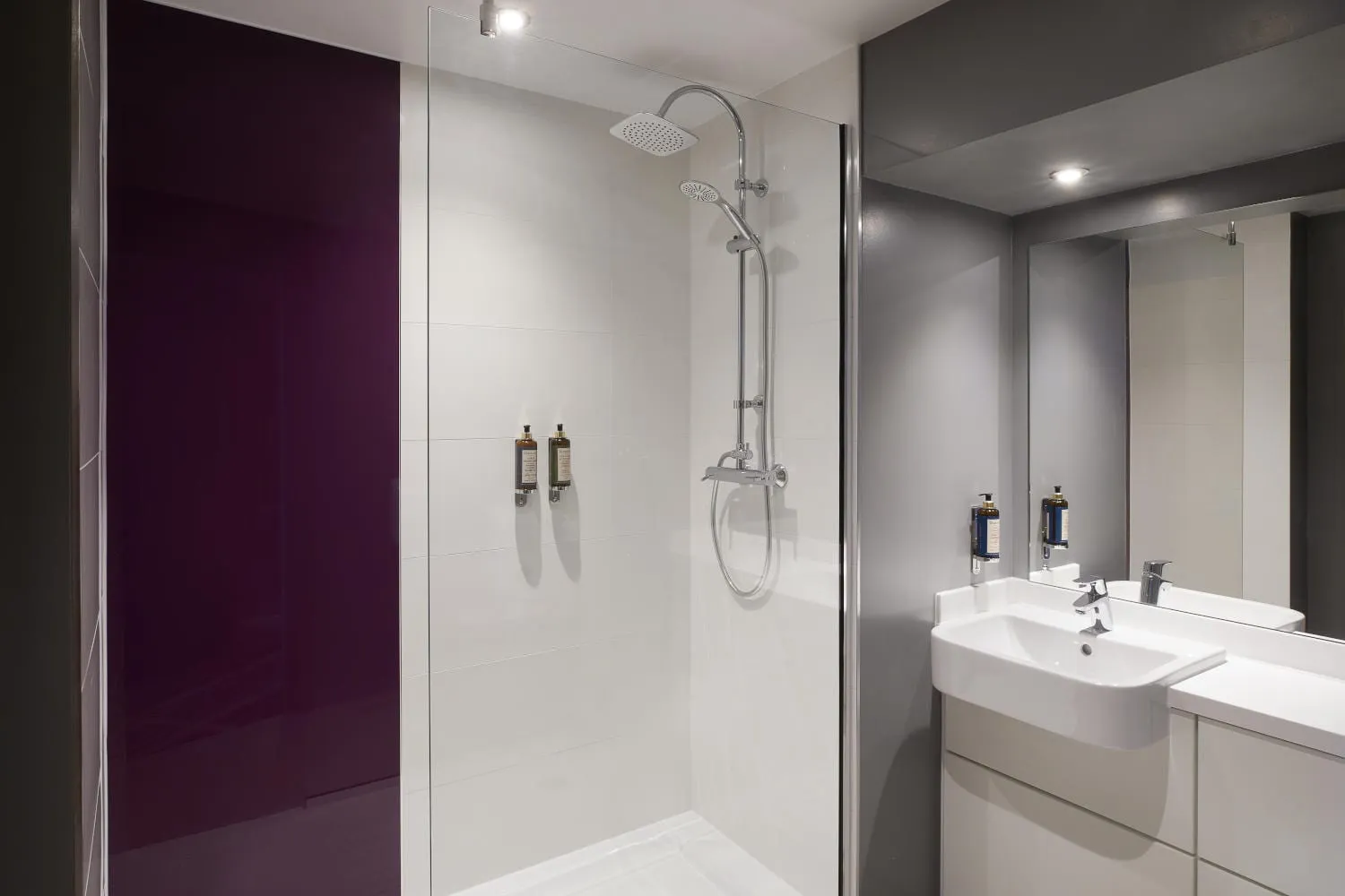 The bathroom at Premier Inn London Stratford, with a purple glass shower panel in the brand's signature accent colour